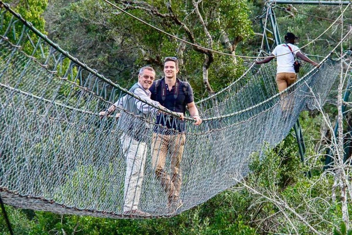 dois homens atravessando uma ponte suspensa na floresta