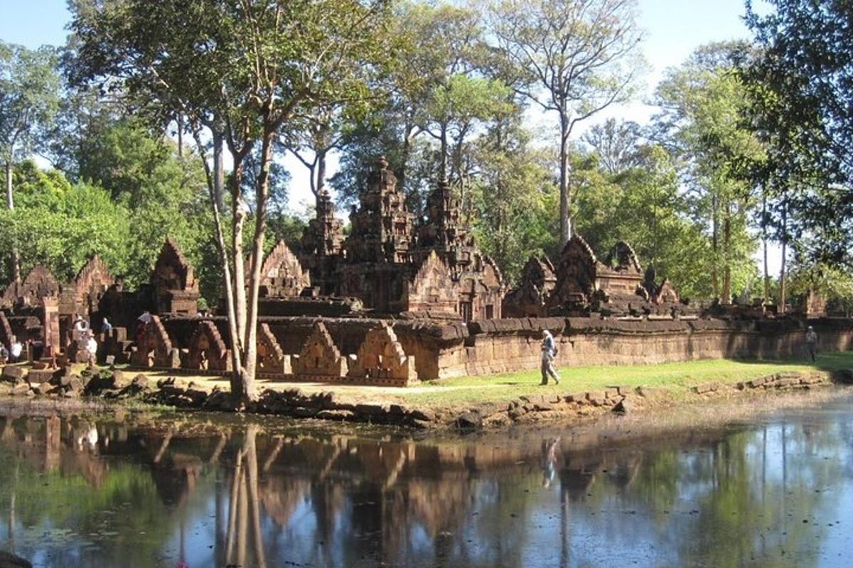 una persona caminando junto a un río frente a un templo