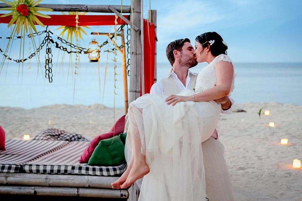 una sposa e uno sposo che si baciano sulla spiaggia