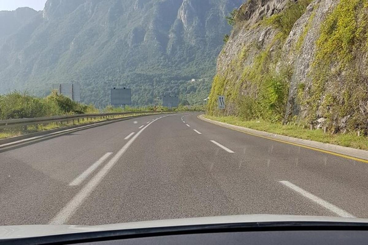 Una vista desde el parabrisas de una carretera con montañas.