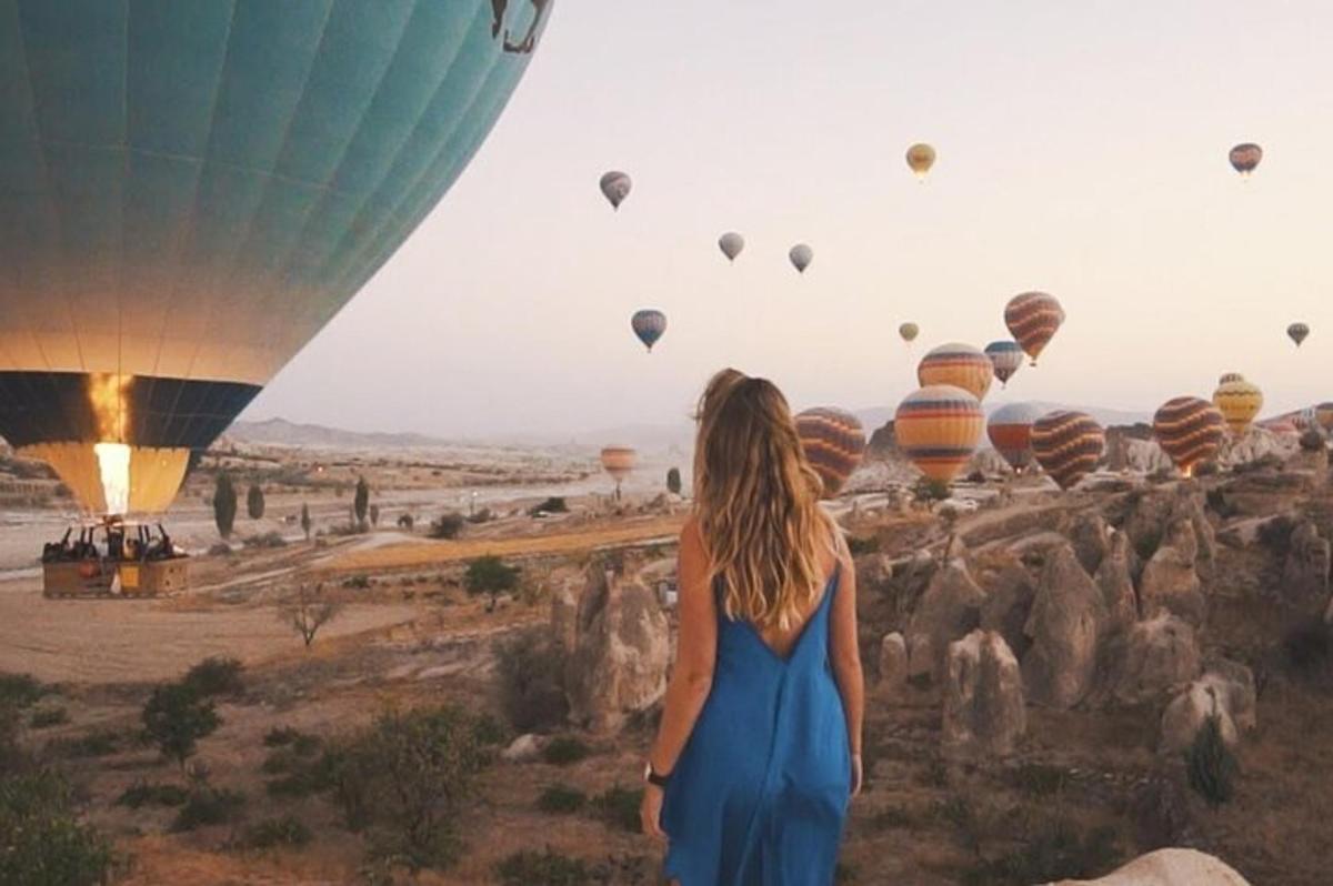 seorang wanita berpakaian biru melihat belon udara panas