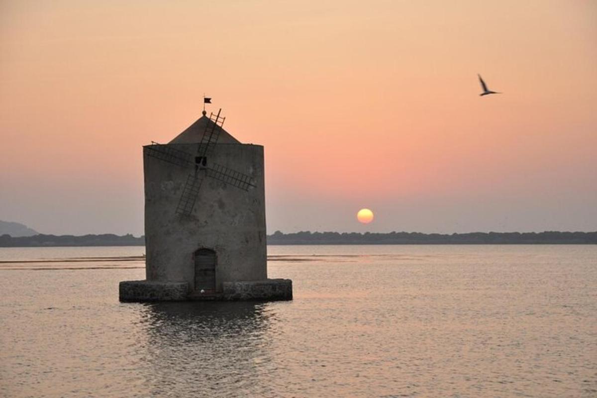 un far a l'aigua amb una posta de sol al fons