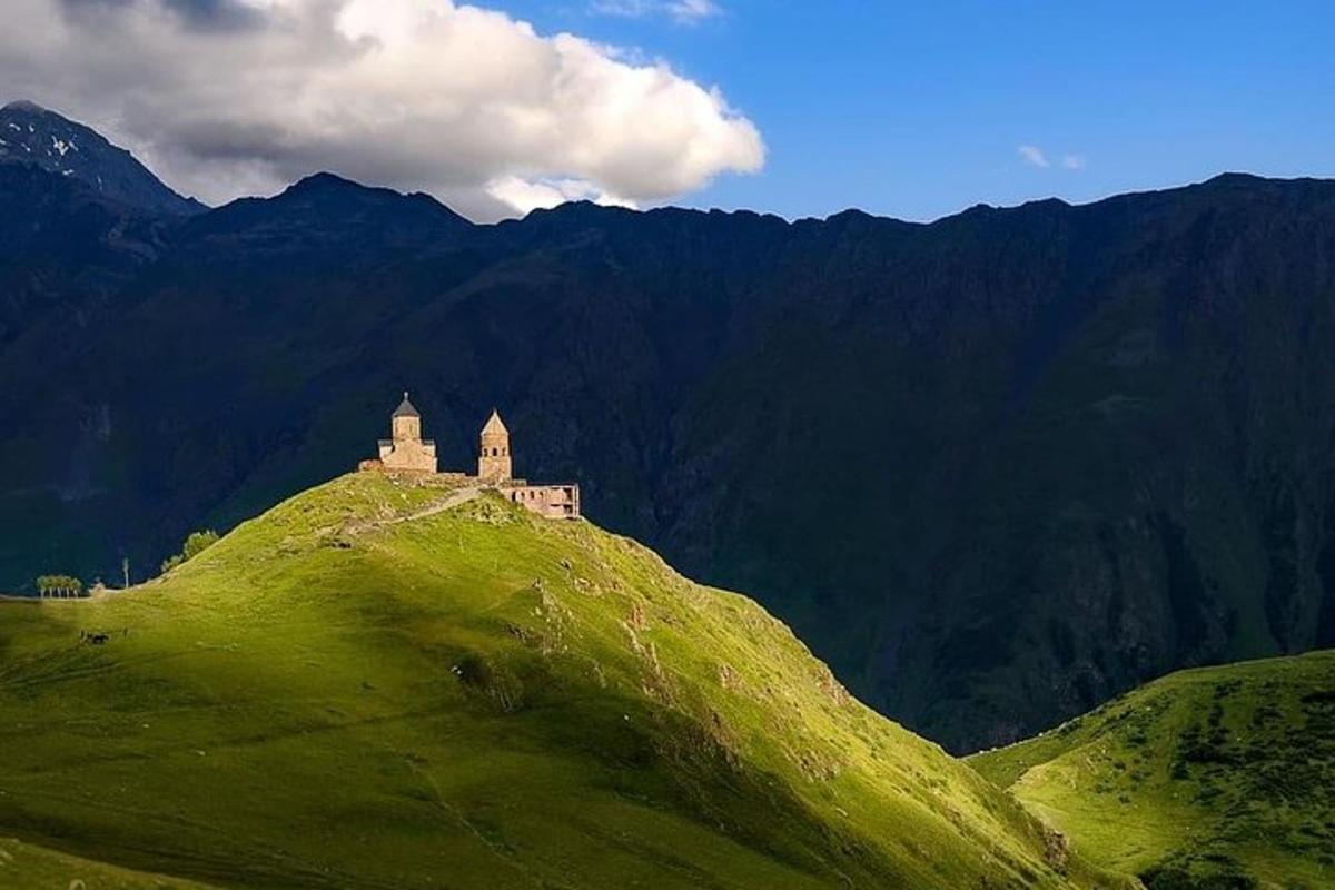 hrad na vrcholu zeleného kopce s horami