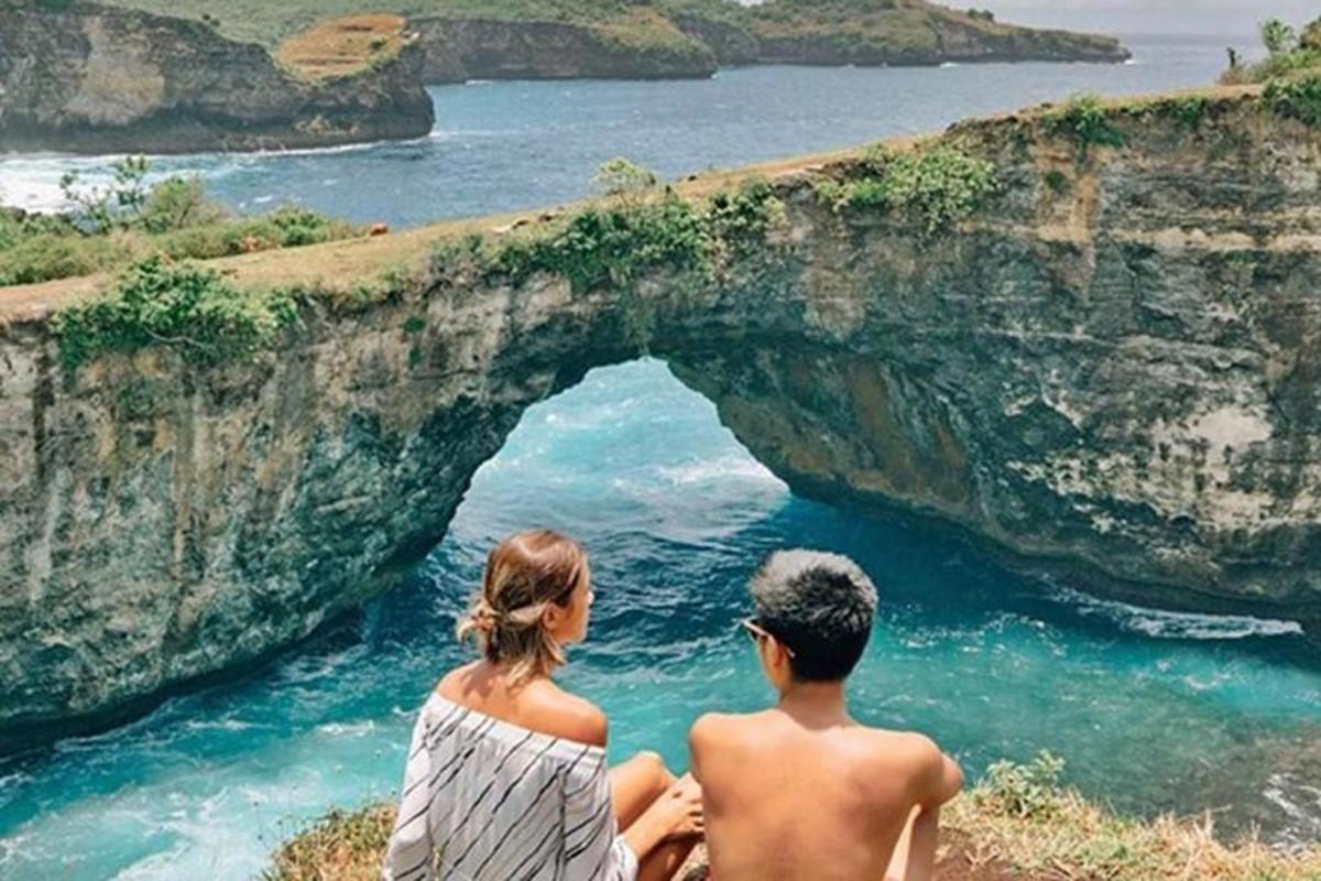 un home i una dona asseguts en un penya-segat mirant l'oceà