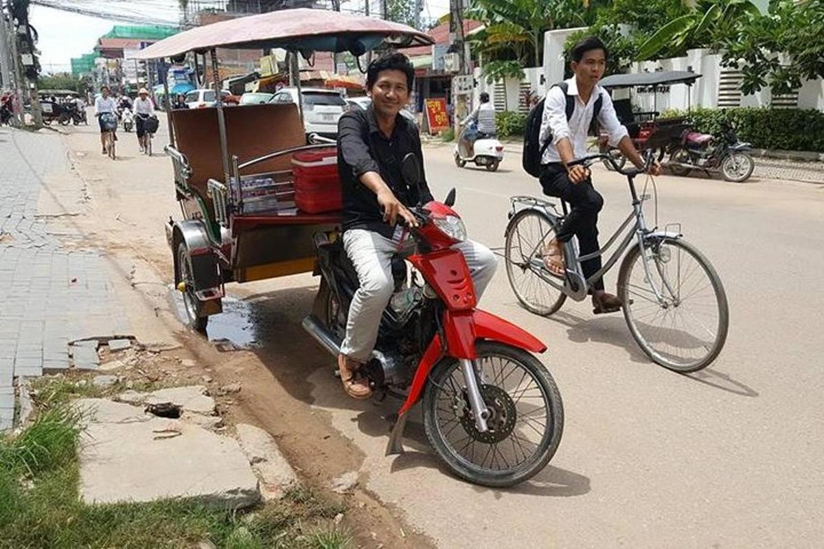 un home que condueix una motocicleta vermella amb un home en una bicicleta