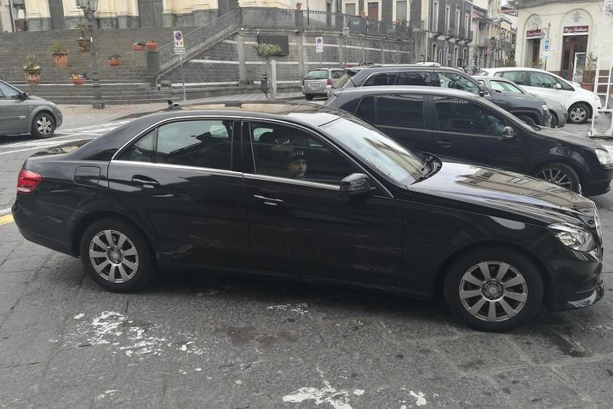 egy fekete autó, aminek az ablakában egy kutya ül