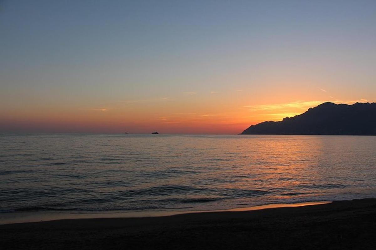 sončni zahod nad oceanom z goro v ozadju