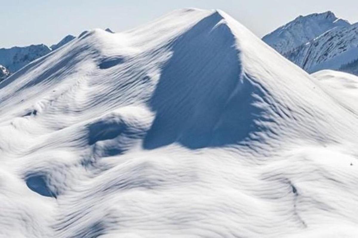 Una montaña cubierta de nieve con montañas al fondo.