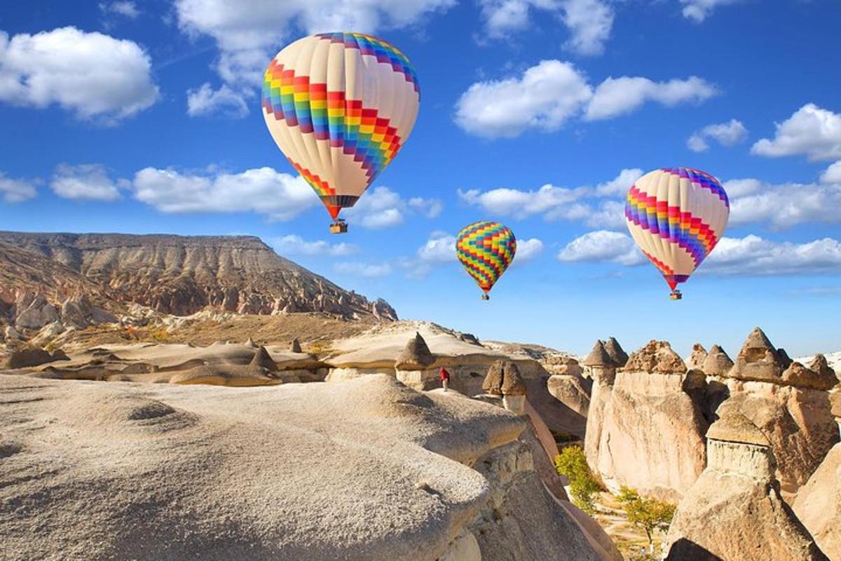 tre mongolfiere che volano sopra un paesaggio roccioso