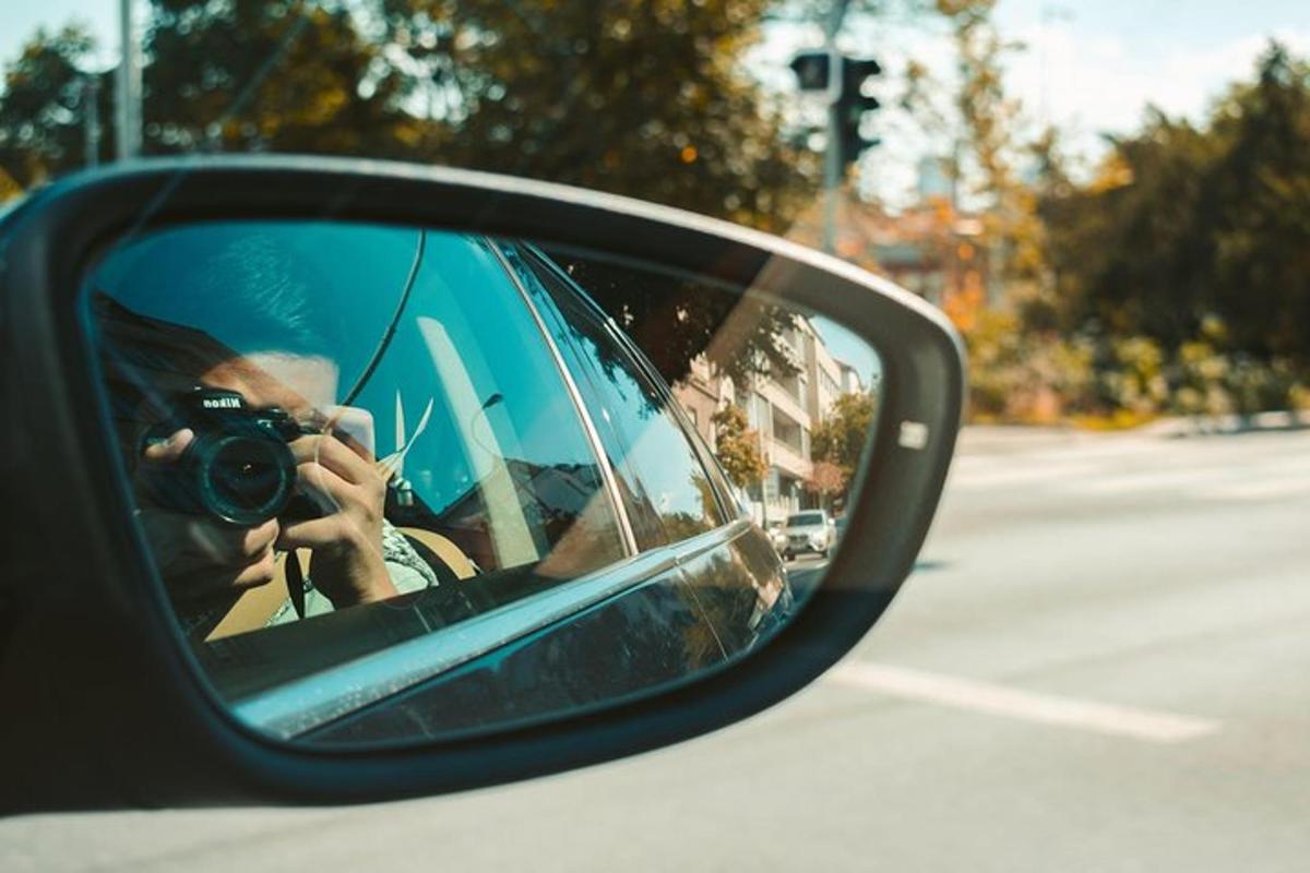 žena fotící auto v bočním zrcátku