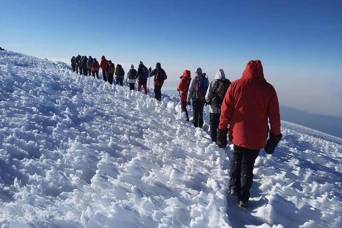 skupina ljudi, ki se vzpenjajo na zasneženo goro