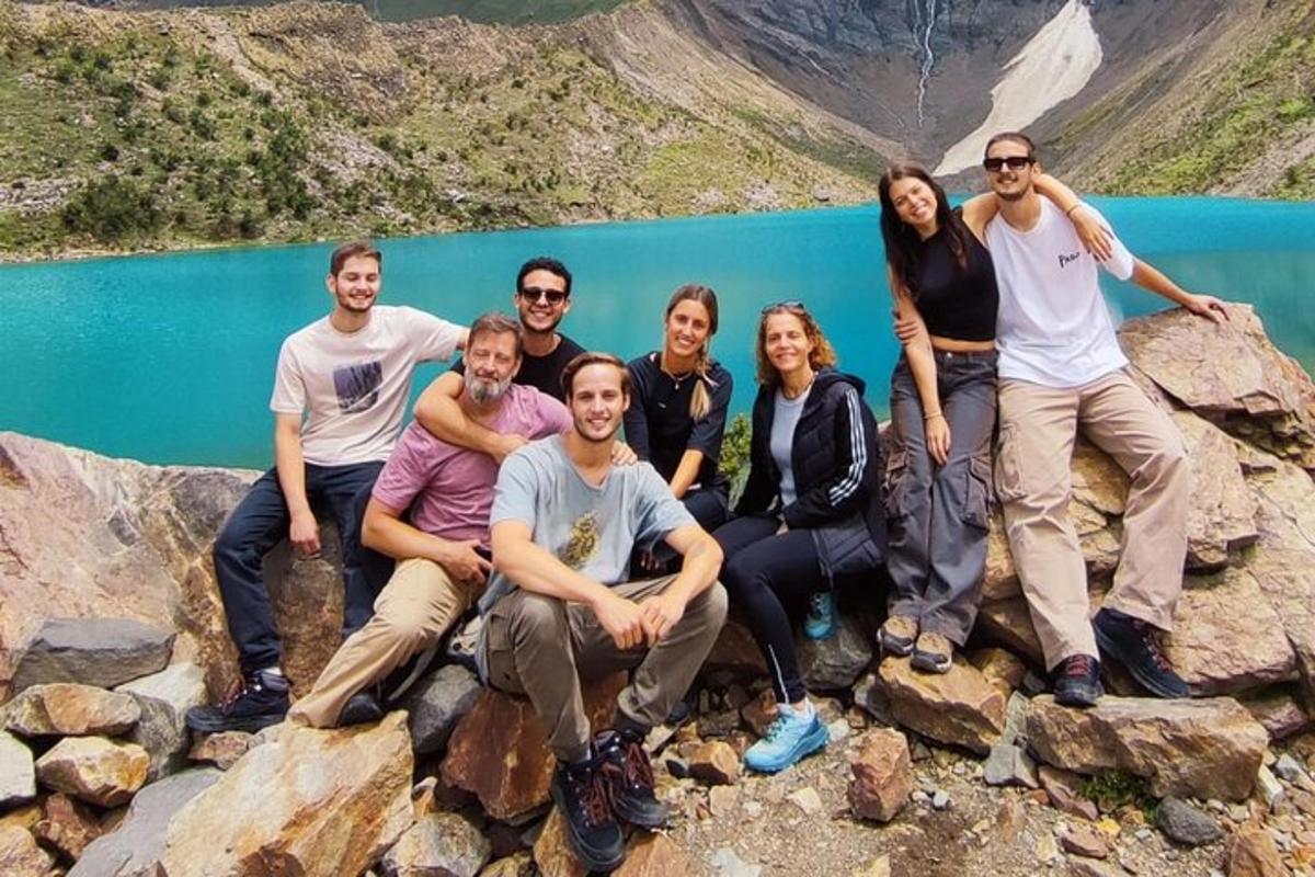un grup de oameni așezați pe stânci lângă un lac
