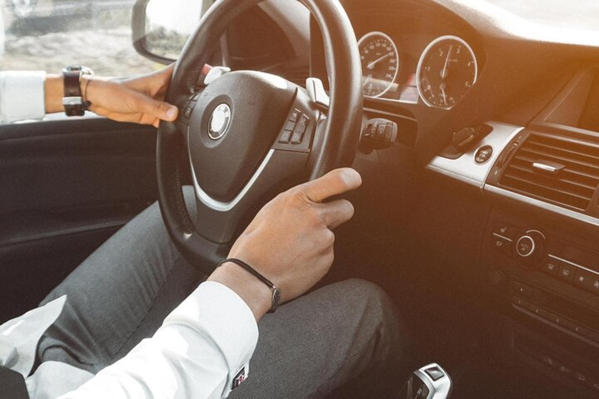 osoba řídící auto a zároveň držící volant
