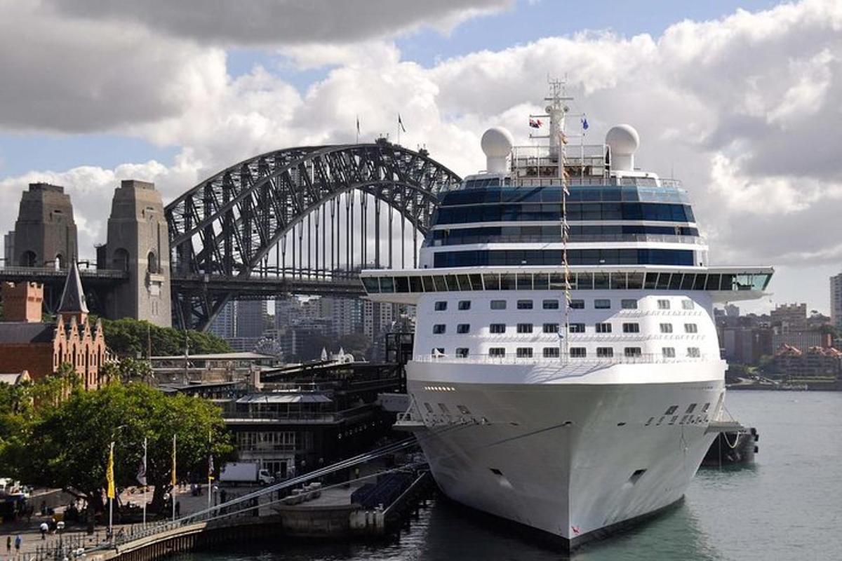 a cruise ship docked in a harbor with a bridge