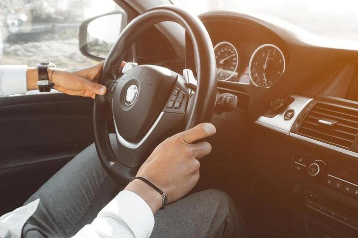 eine Person, die ein Auto fährt und dabei das Lenkrad festhält