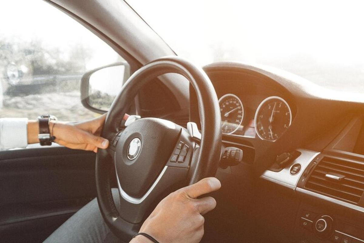 osoba řídící auto s volantem