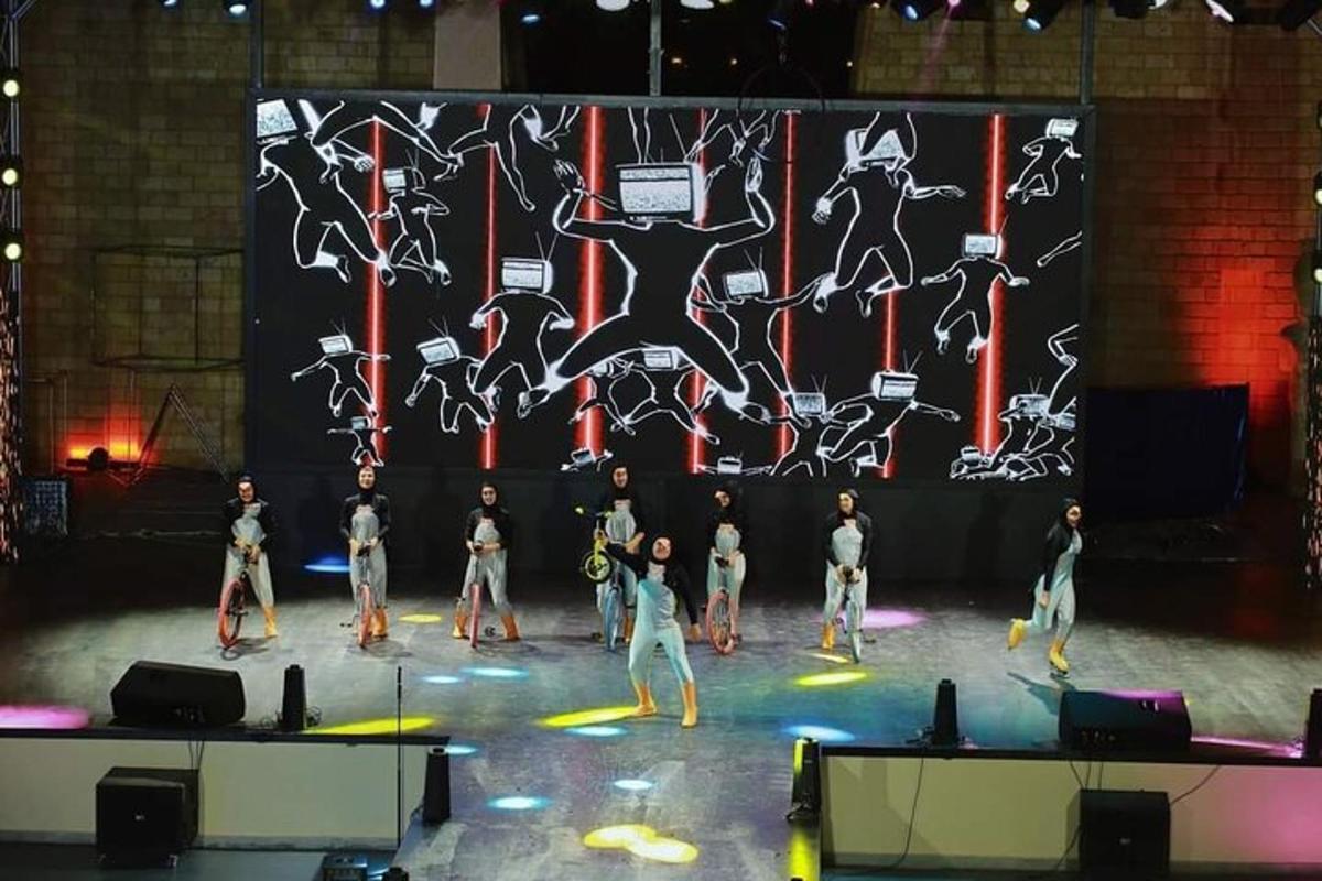 un gruppo di ballerini su un palco davanti a un grande schermo