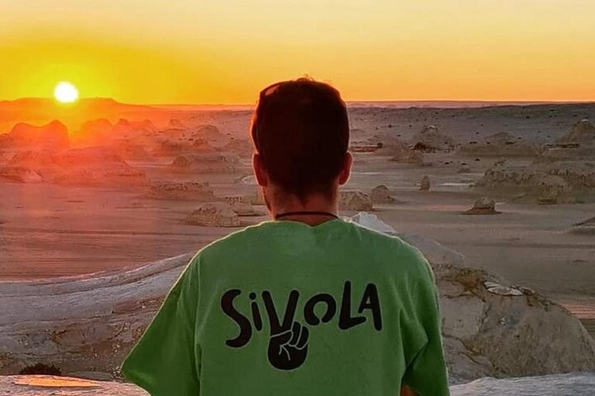 a young man is looking at the sunset