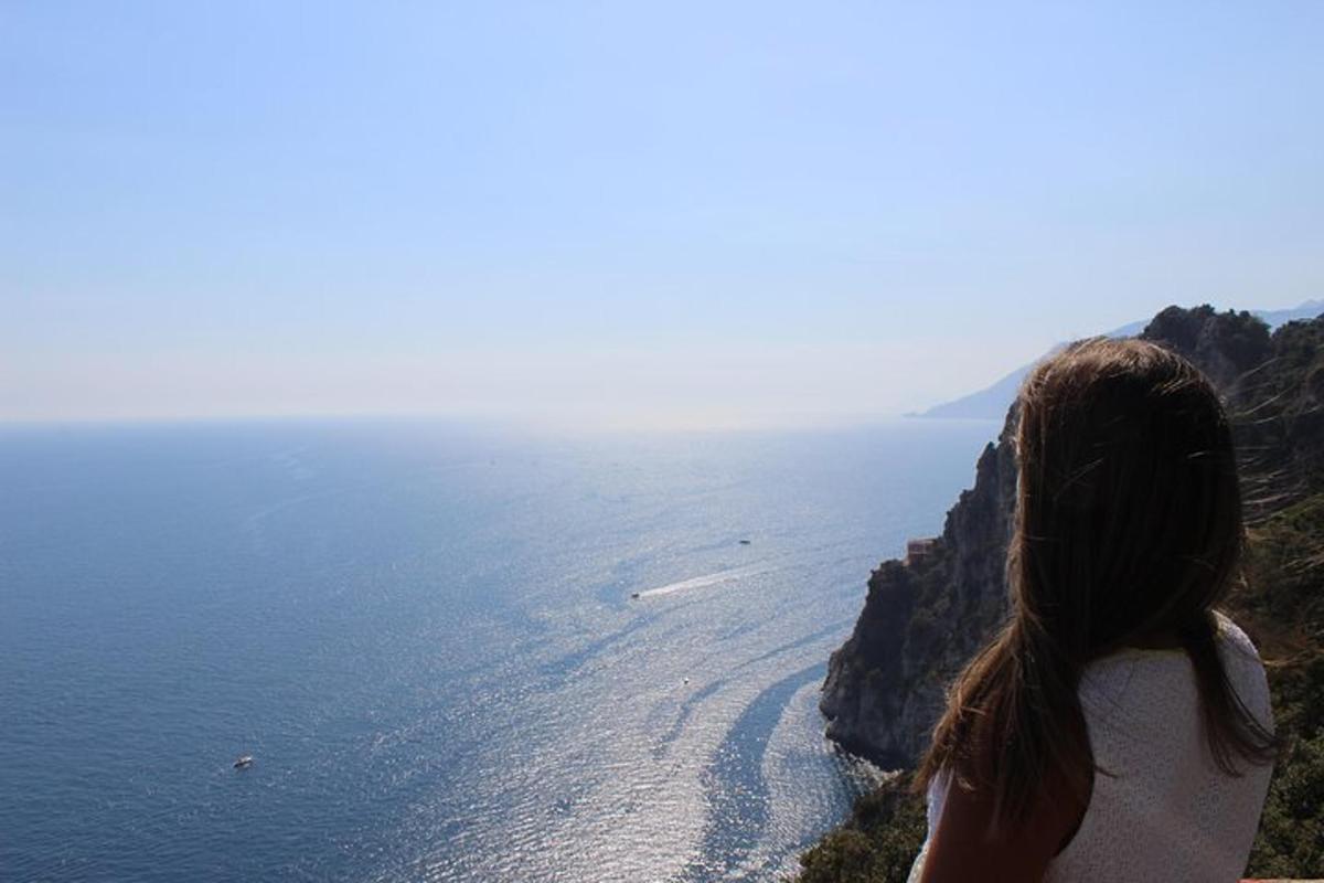 eine Frau, die auf einer Klippe steht und auf den Ozean blickt
