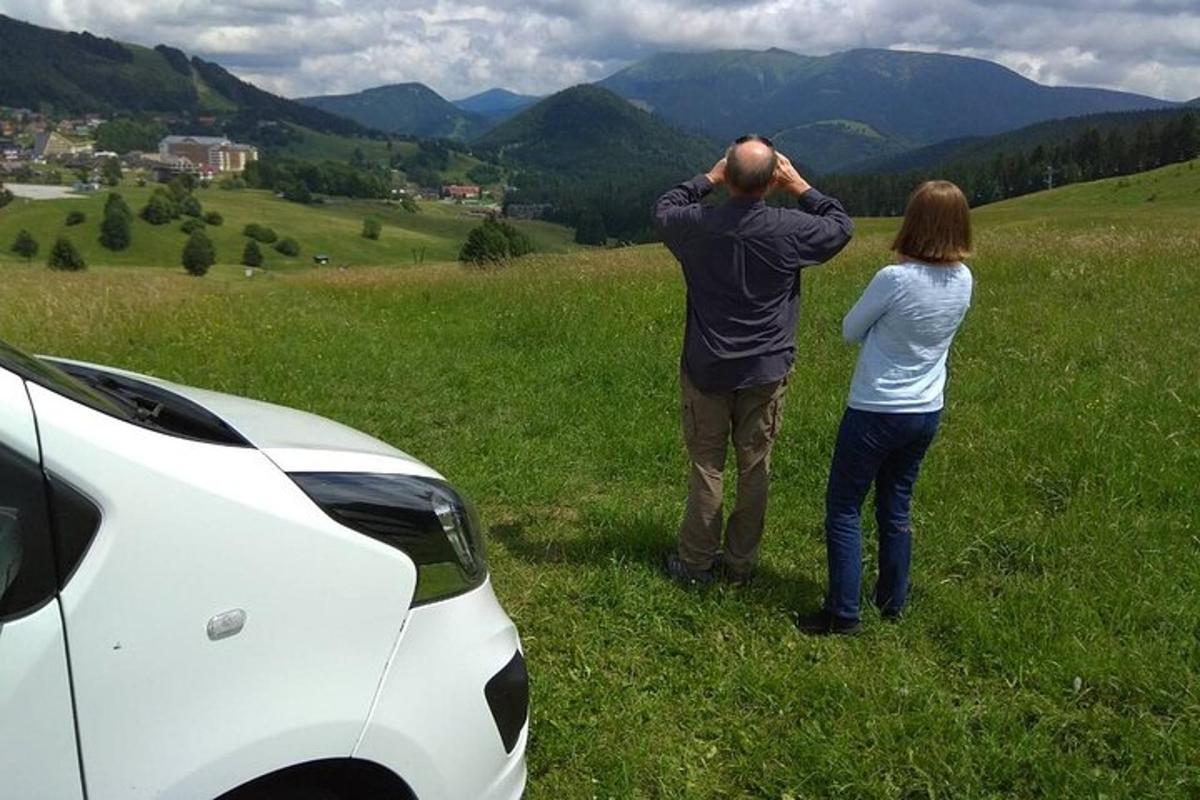 a man and a woman standing in a field near a car