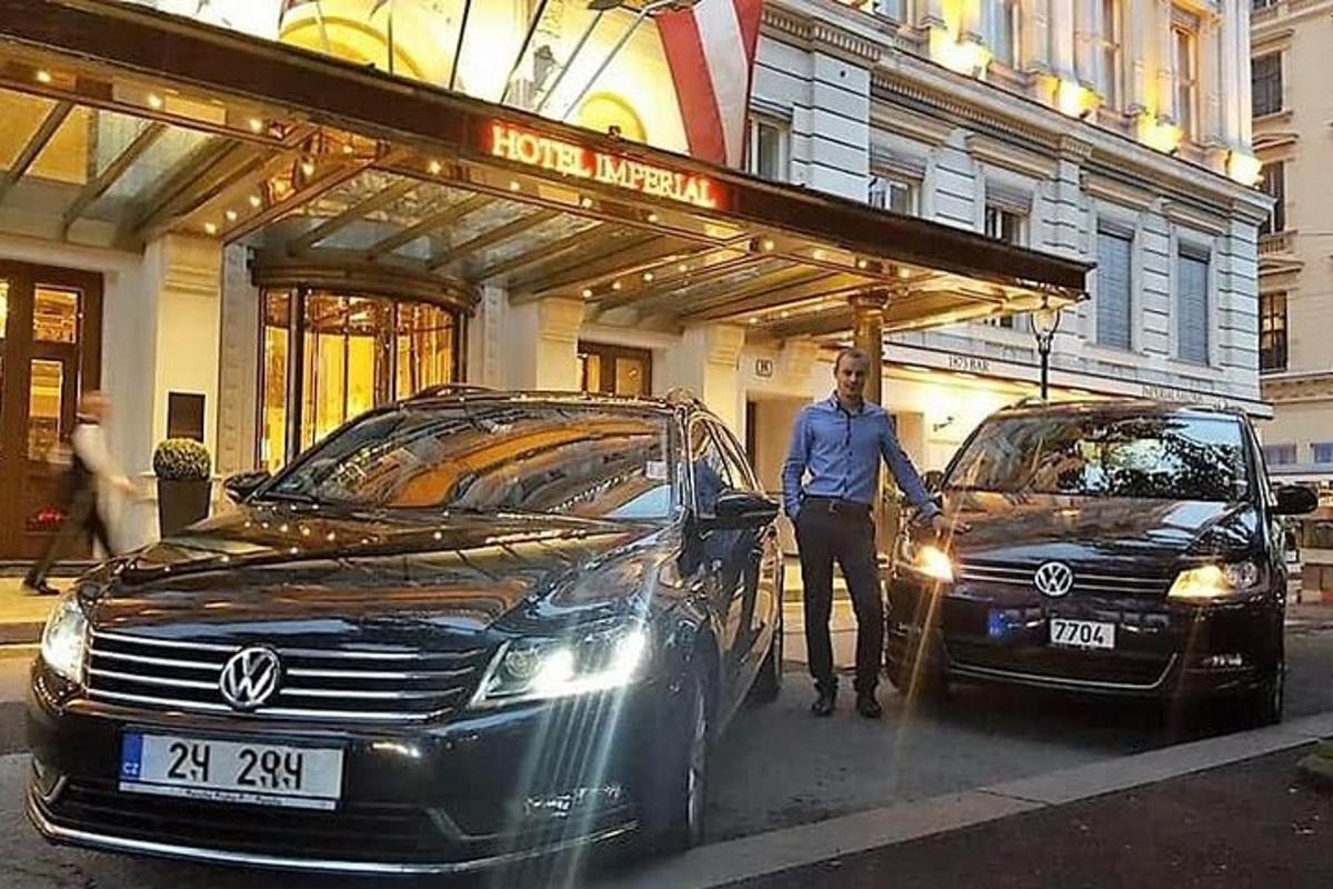 một người đàn ông đứng cạnh hai chiếc xe trước một tòa nhà