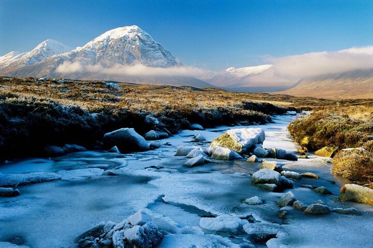 una montagna innevata in lontananza con un fiume