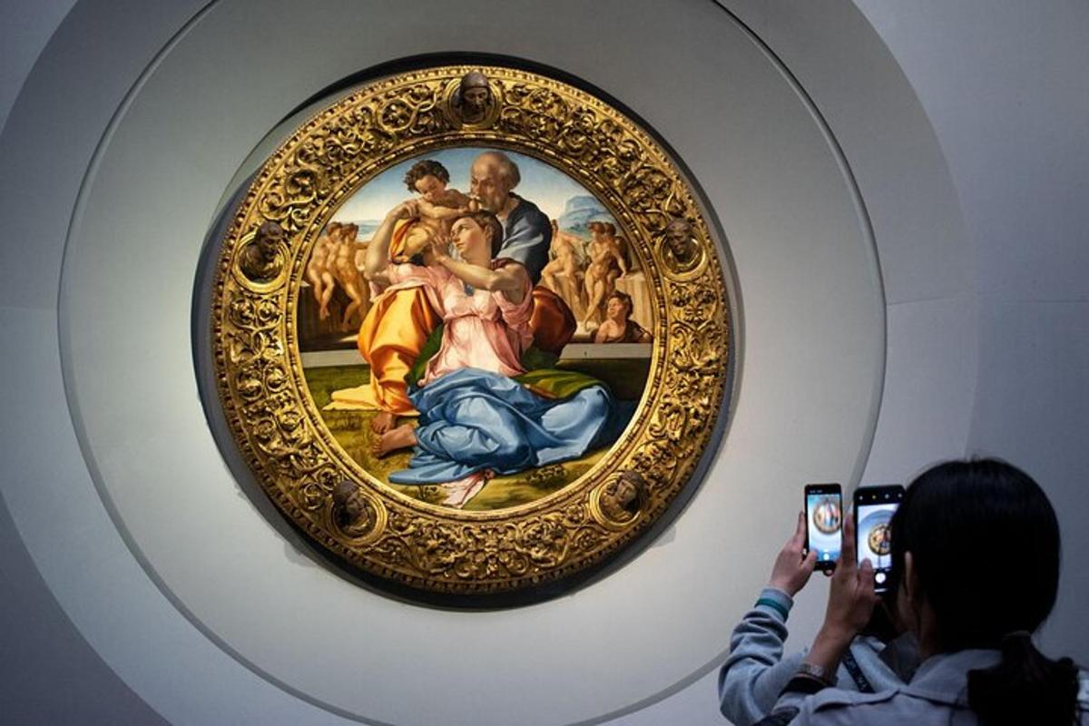 a woman taking a picture of a painting in a museum
