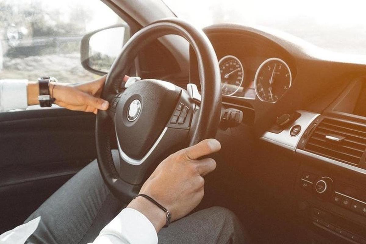 seseorang memandu kereta dengan tangan mereka pada stereng