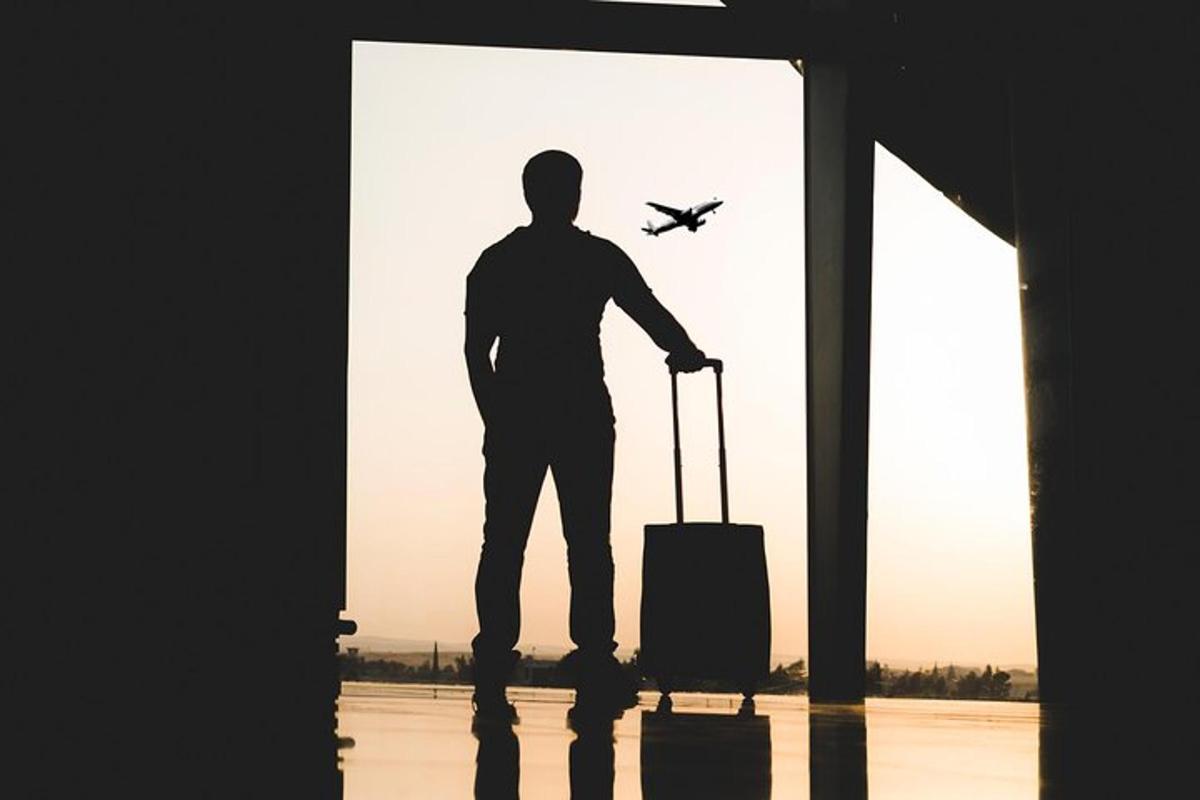 Un hombre parado en un aeropuerto con una maleta y un avión.
