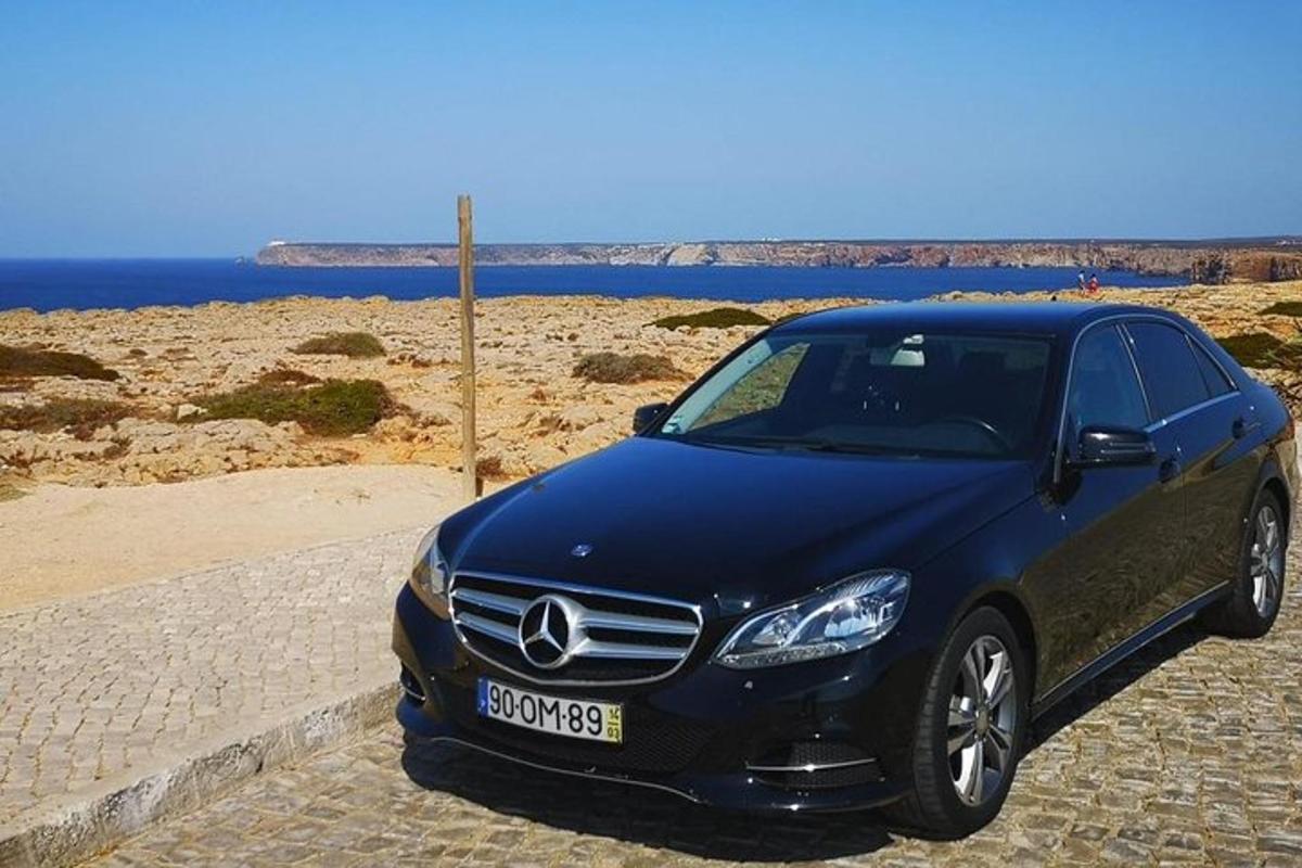 Un coche Mercedes Benz azul aparcado junto a una playa.