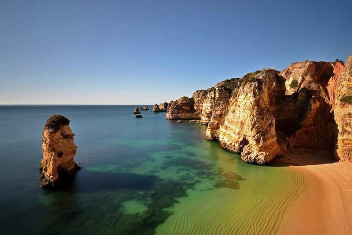 una playa con rocas en el agua al lado de la arena