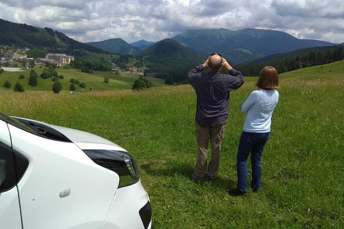 un uomo e una donna in piedi in un campo vicino a un'auto