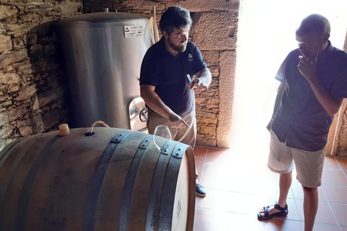 Dos hombres de pie junto a un gran barril de madera