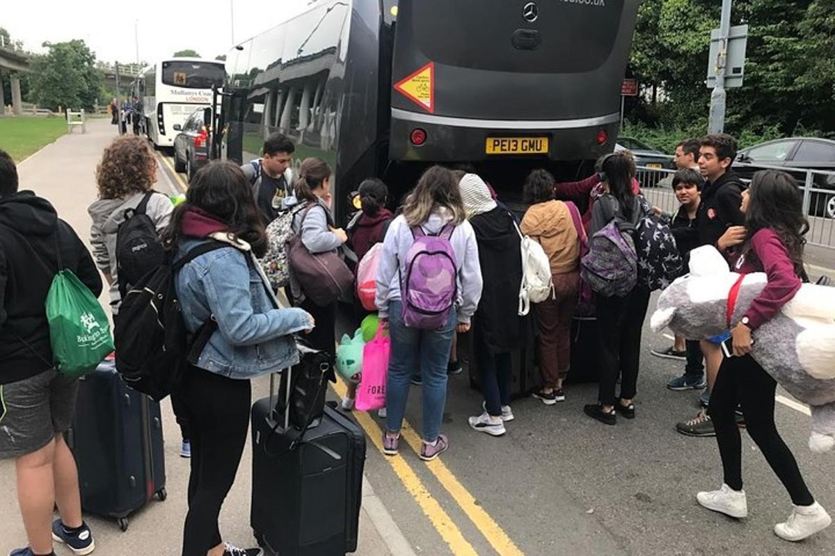 en gruppe mennesker som venter på å komme seg på en buss