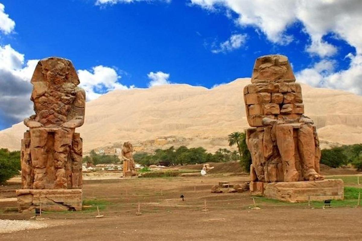 duas estátuas de pedra em um campo com uma montanha ao fundo