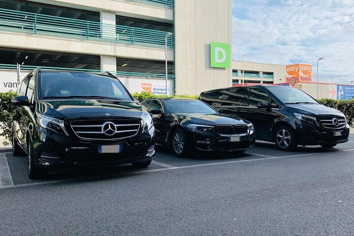 trīs automašīnas novietotas stāvvietā ēkas priekšā