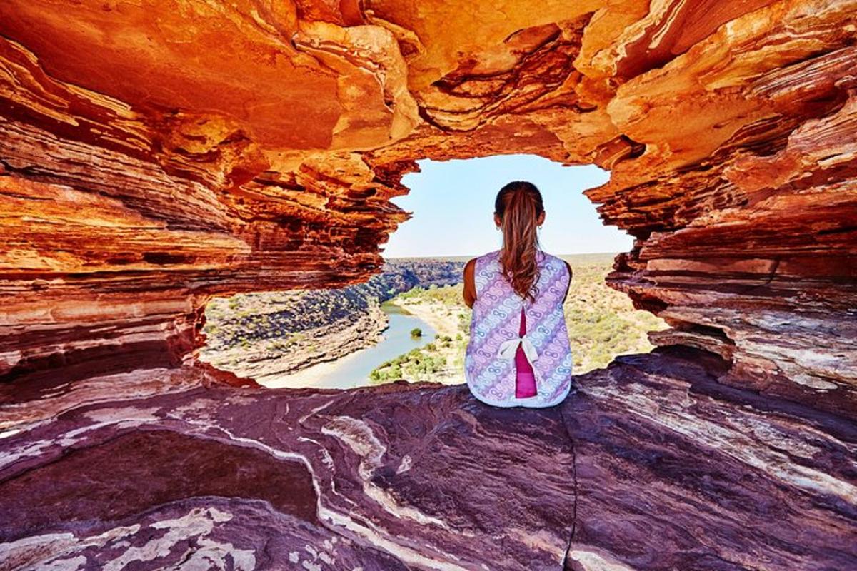 a woman standing in a cave looking out at a river