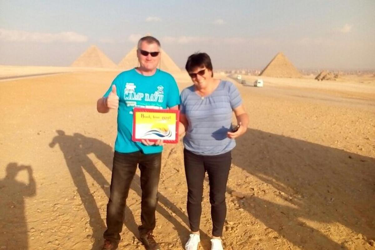 muž a žena držiaci pamätnú tabuľu pred pyramídami
