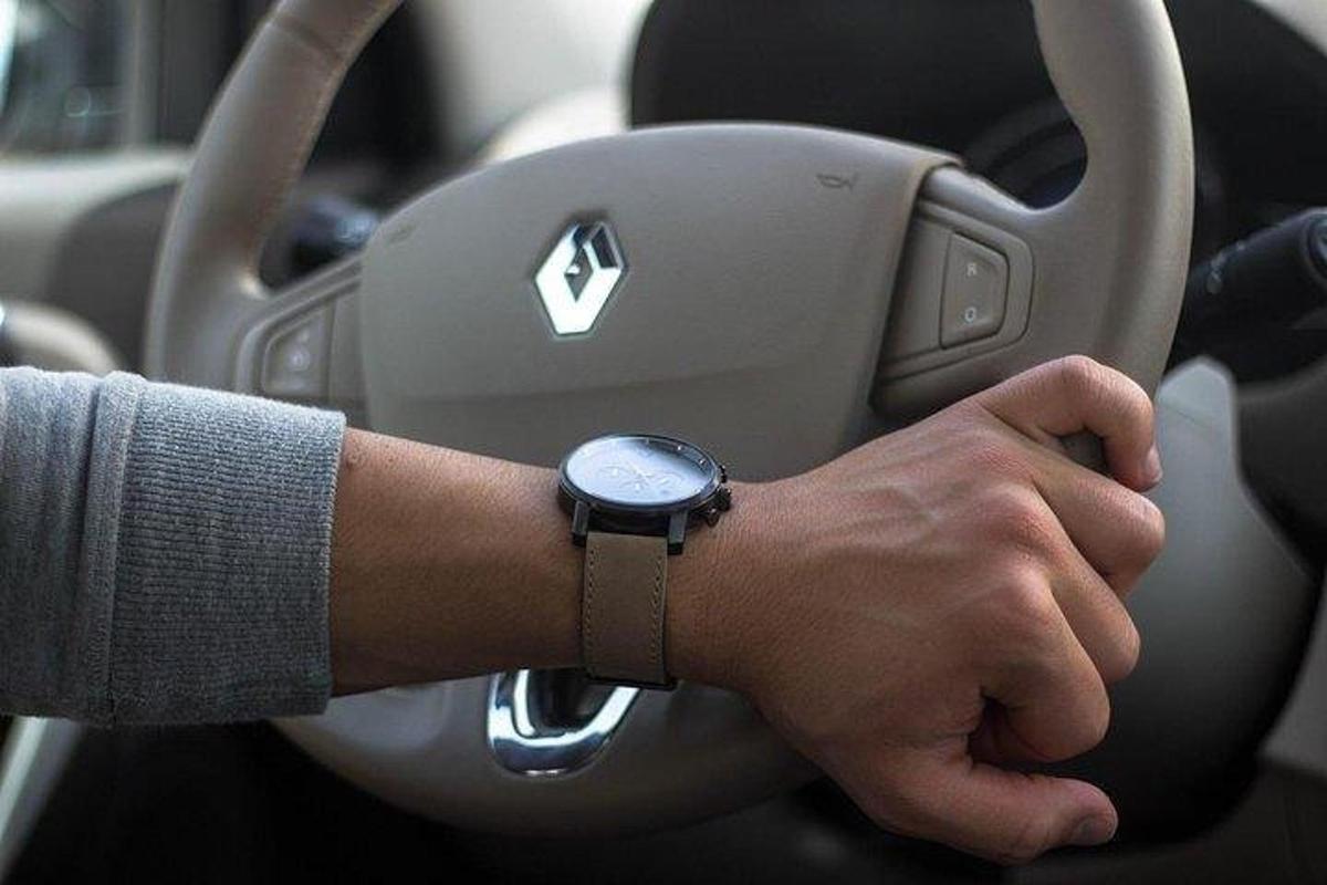 muž řídí auto s hodinkami na paži