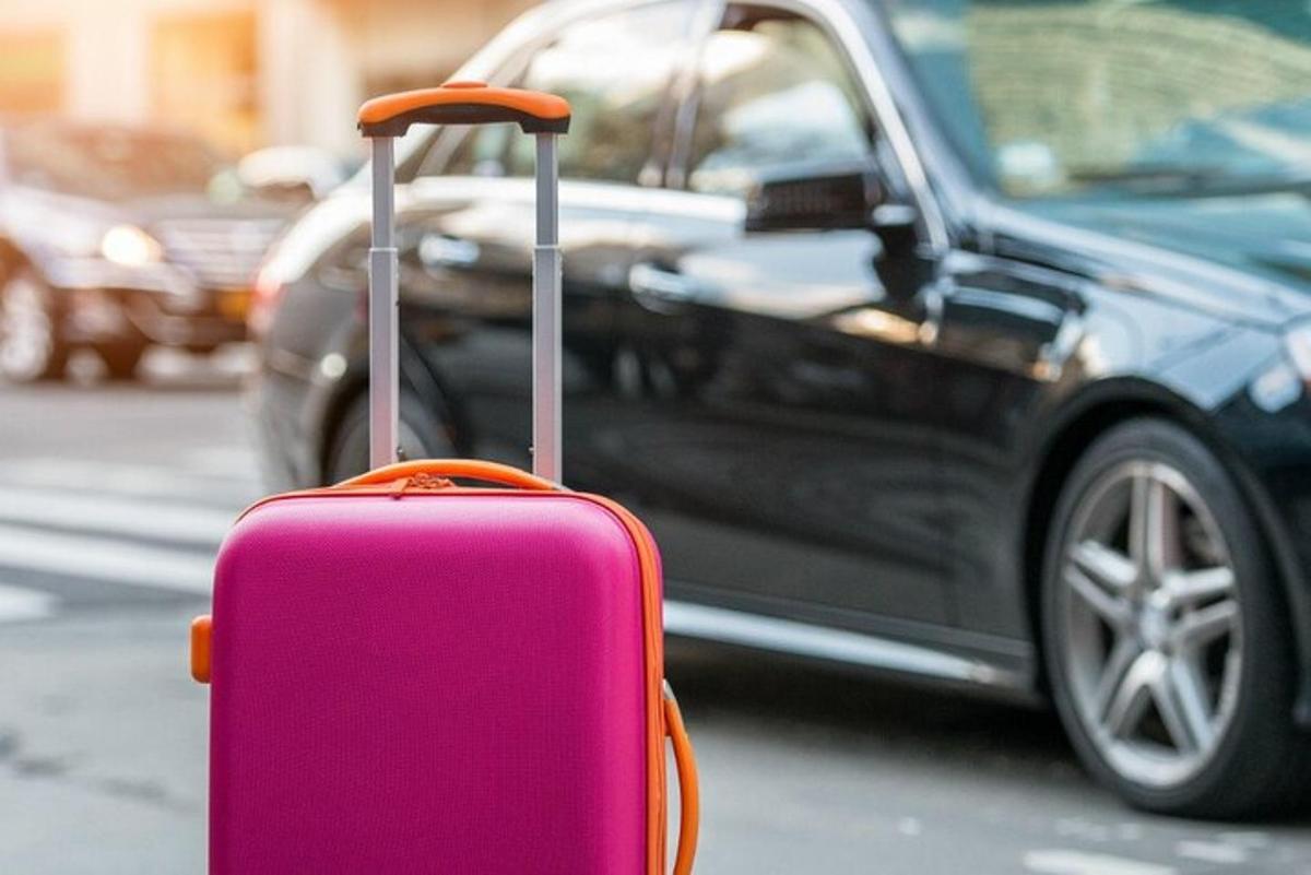 Una maleta rosa sentada delante de un coche.