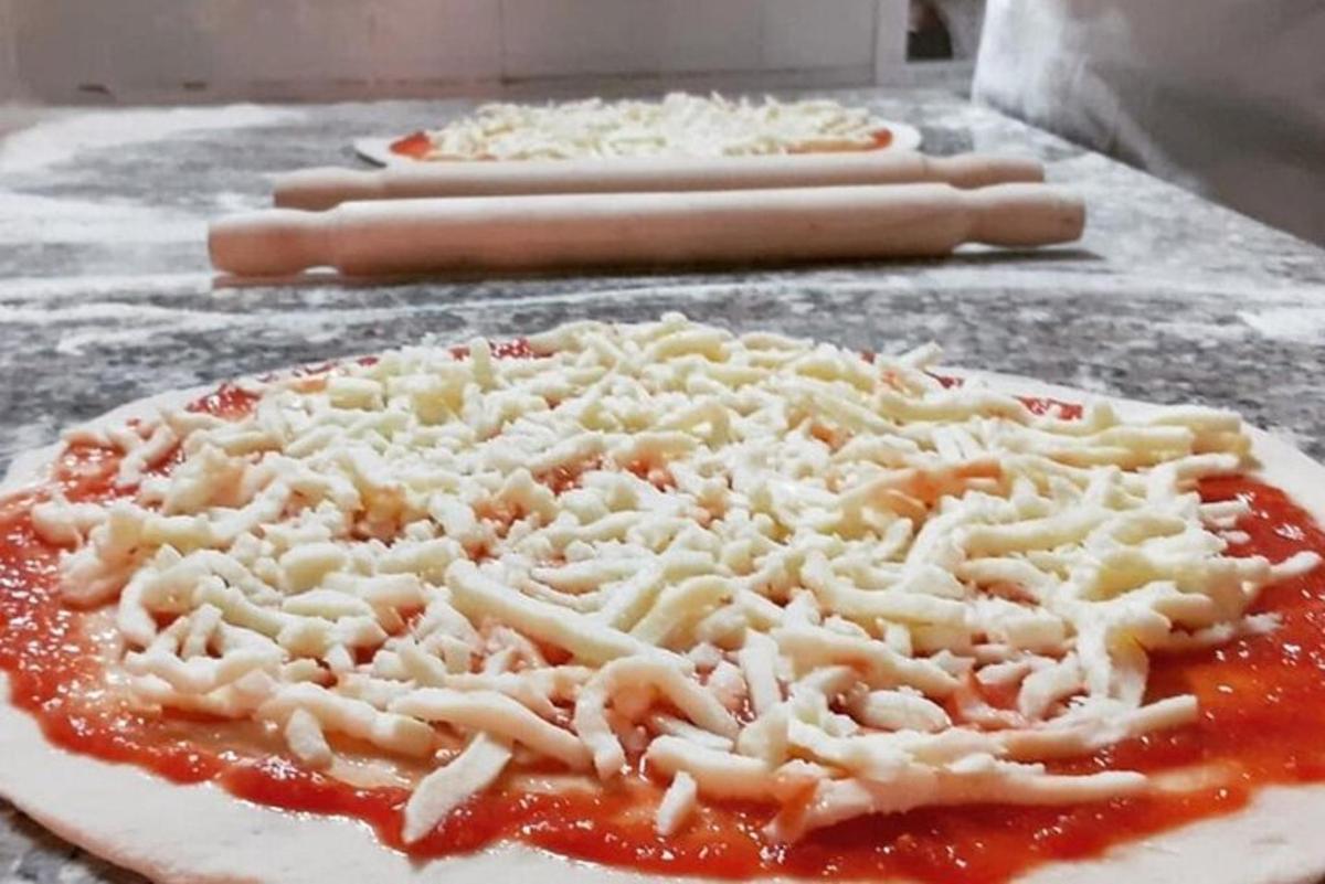 uma pizza com queijo e molho sobre uma mesa