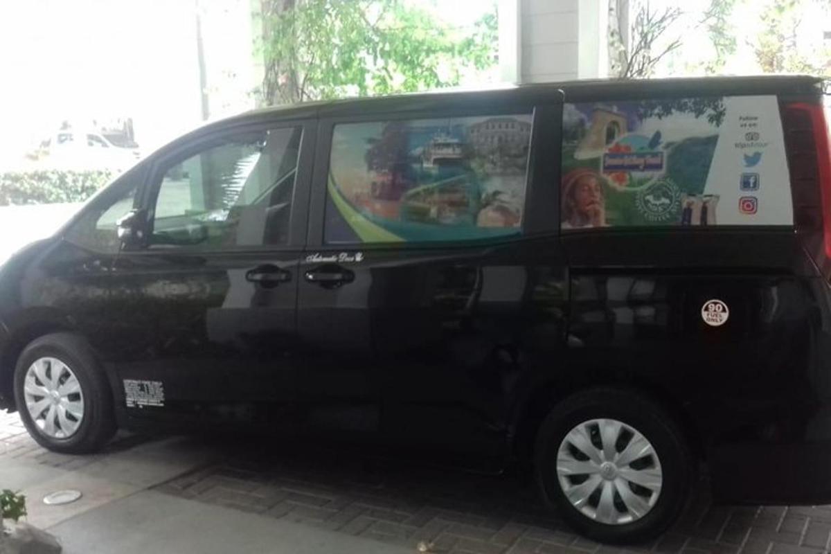 musta pakettiauto pysäköitynä kadulle, jonka kyljessä on kyltti