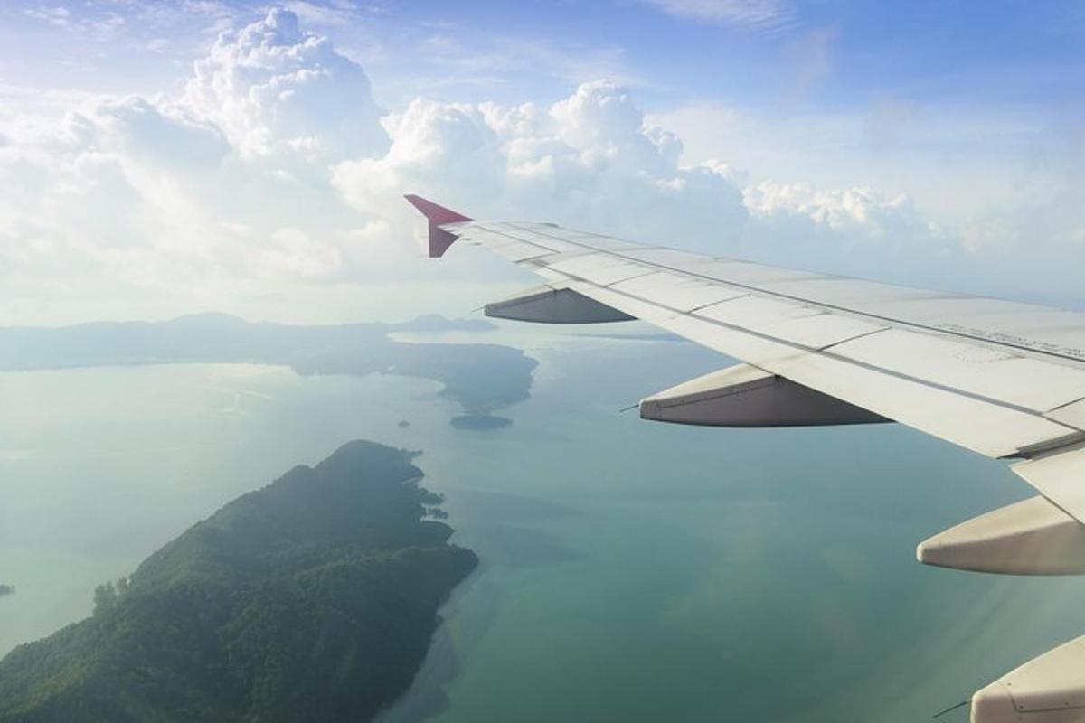 a view of the wing of an airplane flying over the ocean