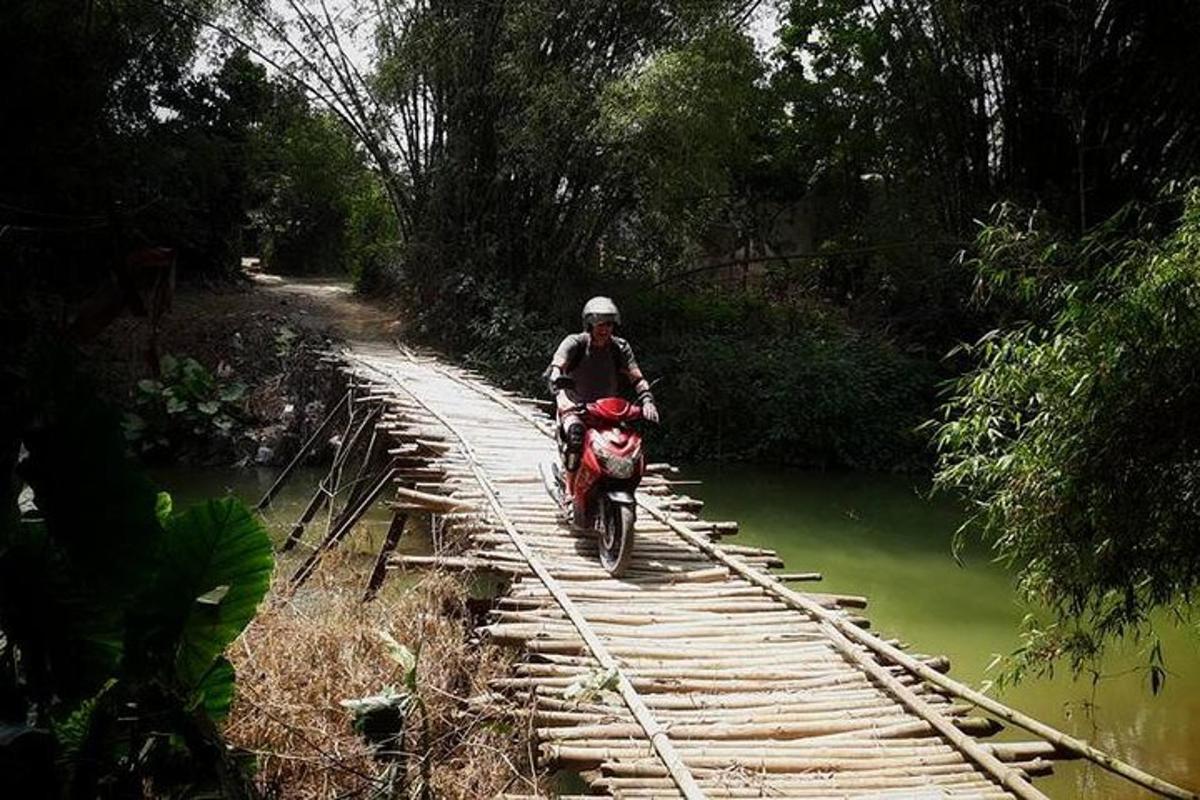 a man riding a motorcycle crossing a bridge over a river