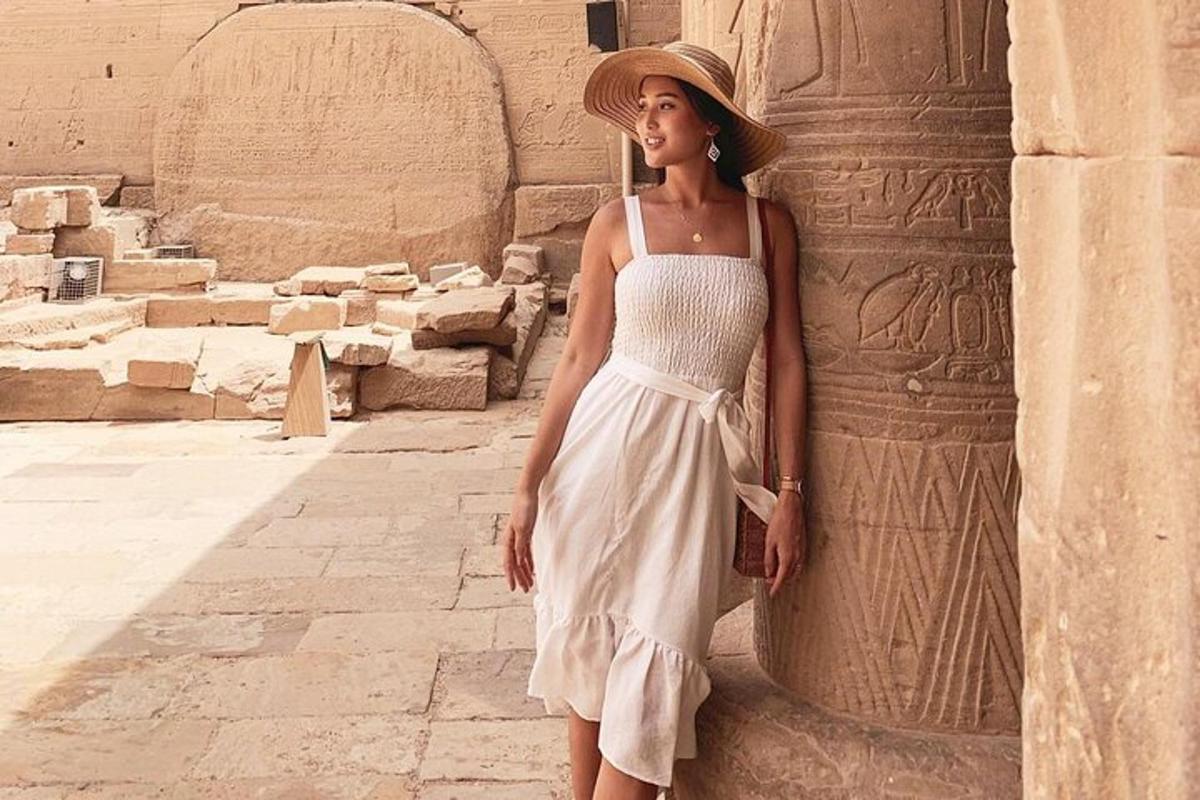 una dona amb un vestit blanc dempeus al costat d'un edifici