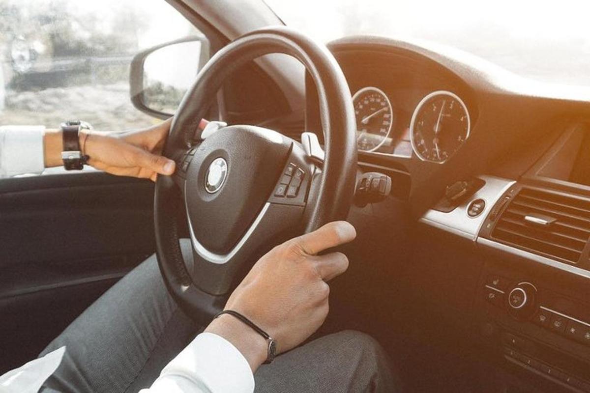 seseorang memandu kereta sambil memegang stereng