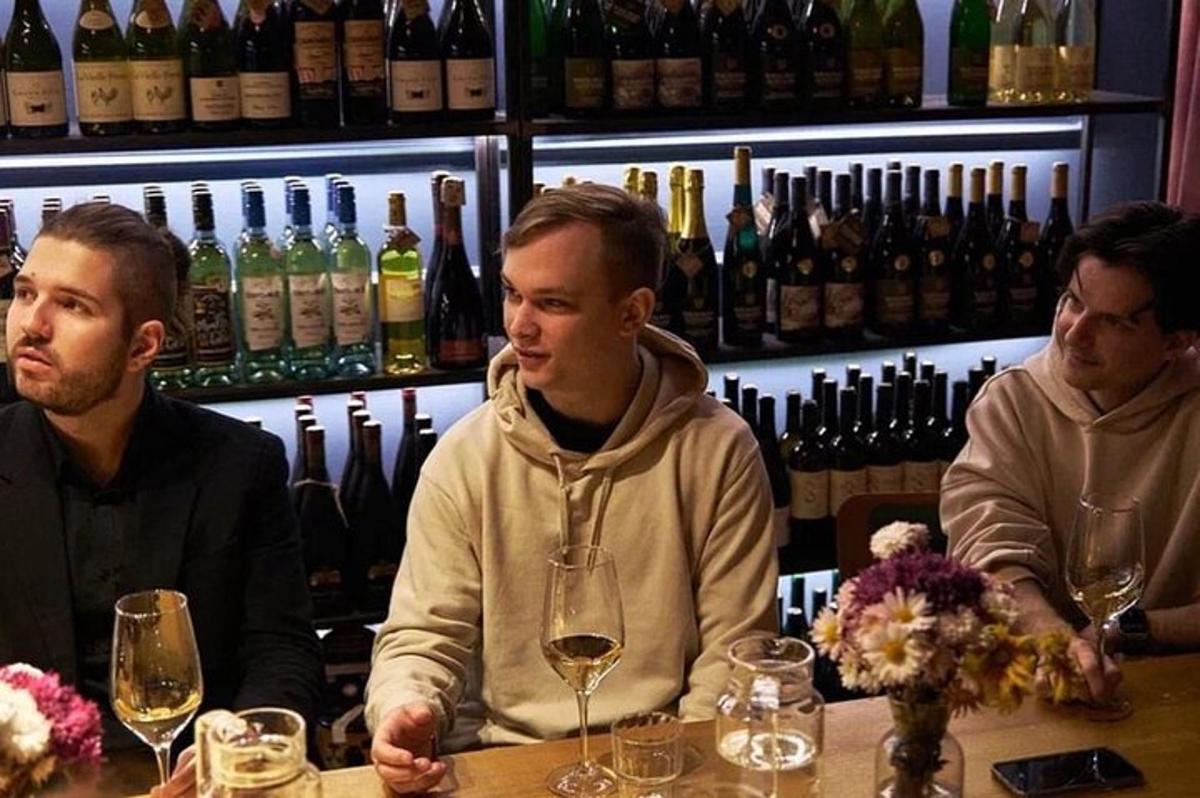 tři muži sedící u baru s vinnými sklenicemi