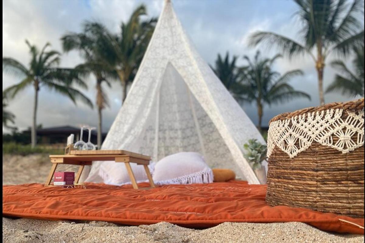 uma cama na praia com uma tenda
