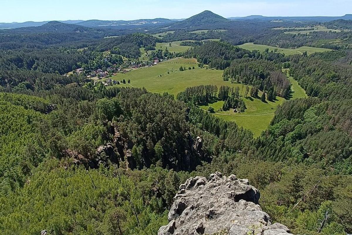 a view of a valley with trees and a rock