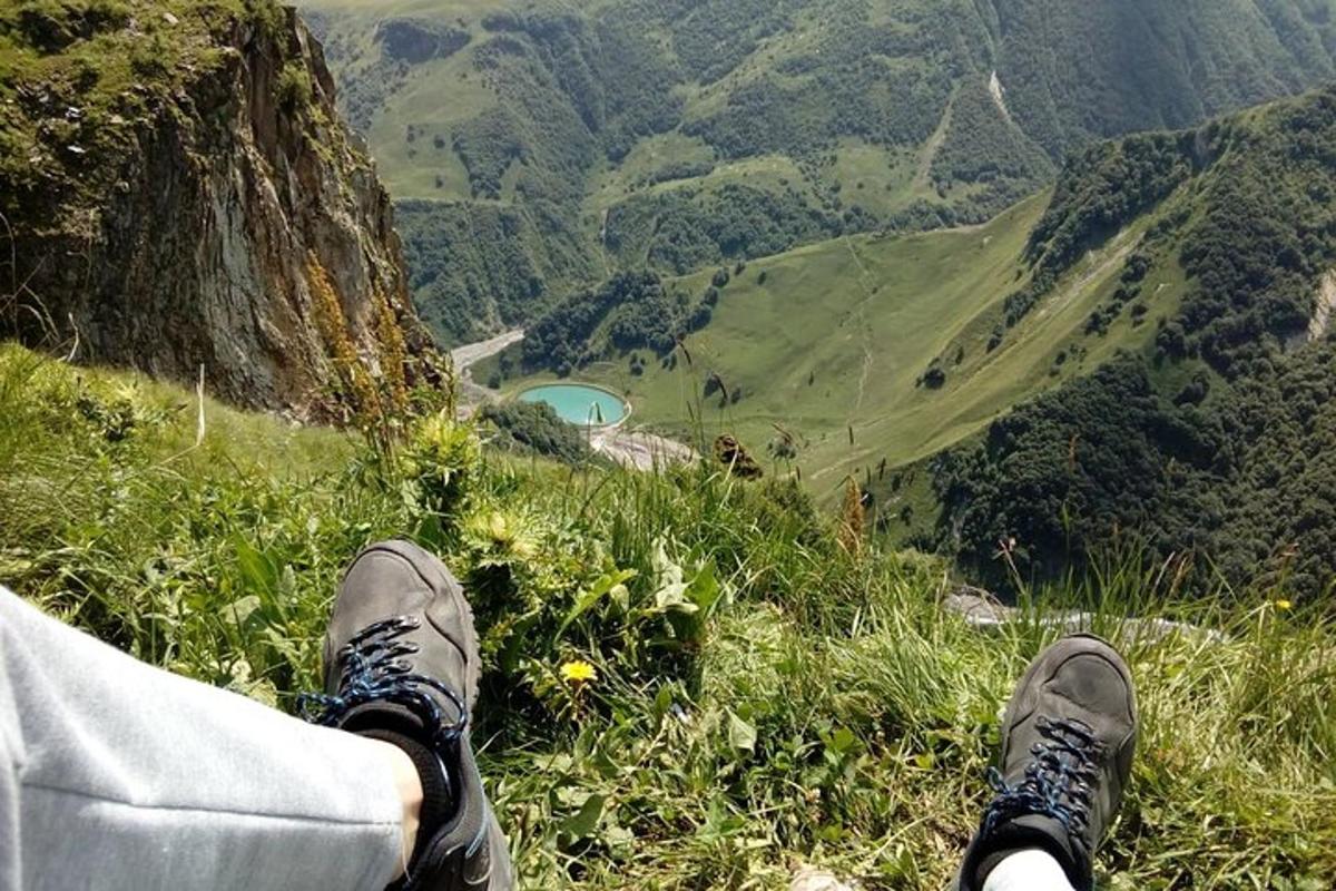 una persona seduta sul bordo di una montagna che guarda verso il basso verso una valle